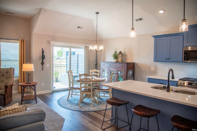 kitchen featuring a breakfast bar area, stainless steel appliances, a sink, visible vents, and vaulted ceiling