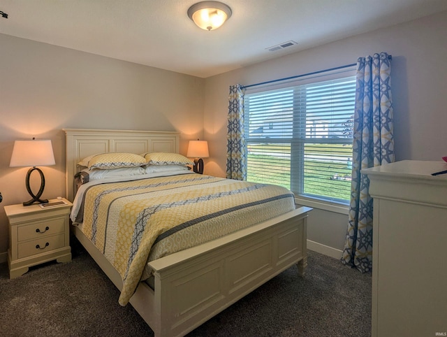 bedroom with dark colored carpet, visible vents, and baseboards