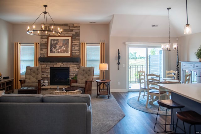 living area featuring a chandelier, a stone fireplace, visible vents, baseboards, and dark wood finished floors