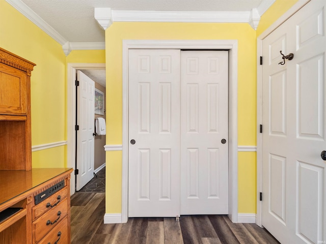 unfurnished bedroom with a textured ceiling, dark wood-type flooring, baseboards, a closet, and crown molding