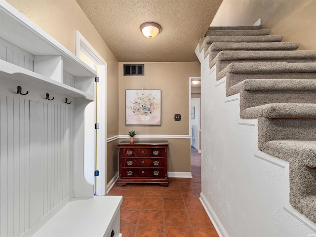 mudroom featuring baseboards, tile patterned flooring, visible vents, and a textured ceiling