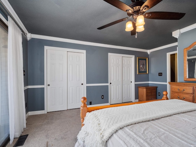 carpeted bedroom with multiple closets, ornamental molding, a textured ceiling, and baseboards