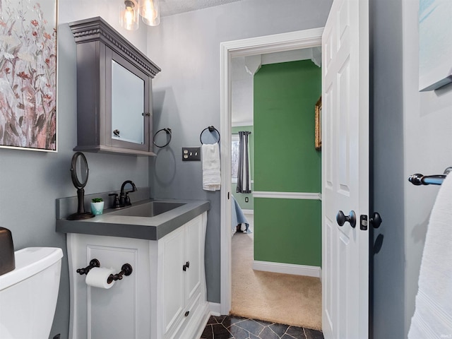 half bath featuring tile patterned flooring, baseboards, vanity, and toilet