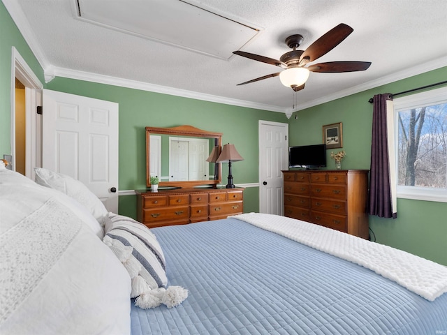 bedroom with a textured ceiling, a ceiling fan, attic access, and crown molding