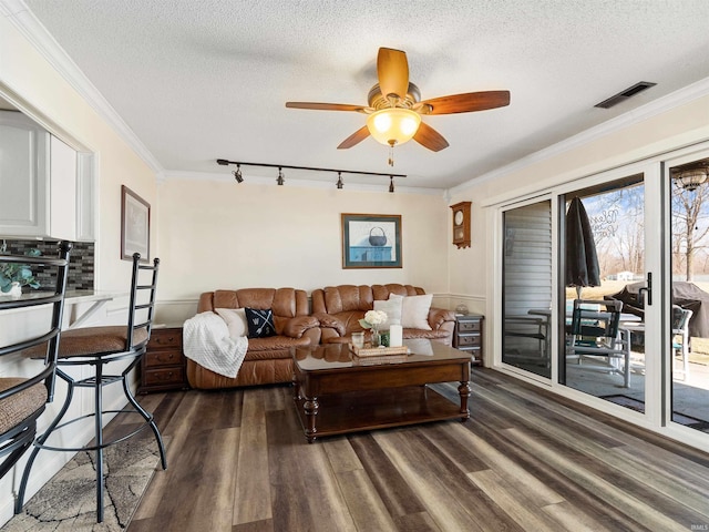 living room with ornamental molding, dark wood-style flooring, visible vents, and a textured ceiling