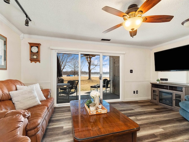 living room featuring ornamental molding, visible vents, a textured ceiling, and dark wood-style floors