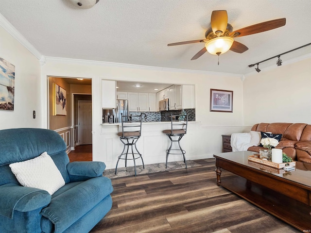 living room with crown molding, a textured ceiling, and dark wood-type flooring