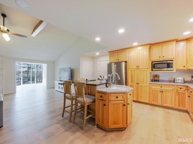 kitchen featuring open floor plan, stainless steel appliances, light wood-type flooring, a sink, and recessed lighting