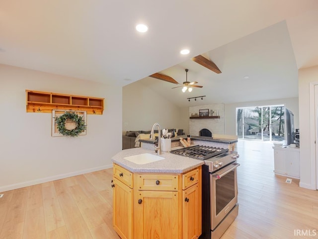 kitchen with open floor plan, a sink, vaulted ceiling, light wood-type flooring, and stainless steel range with gas stovetop