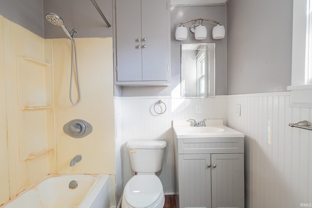 bathroom with toilet, a wainscoted wall, shower / washtub combination, and vanity