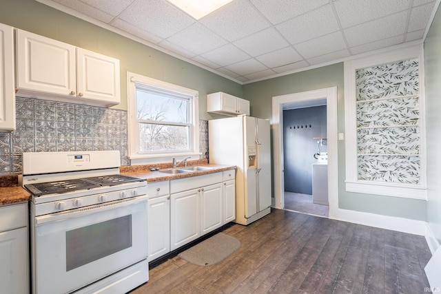 kitchen featuring dark wood-type flooring, white cabinetry, a sink, white appliances, and a drop ceiling