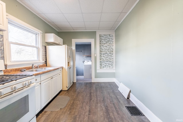 kitchen with white appliances, visible vents, white cabinets, and washer / dryer