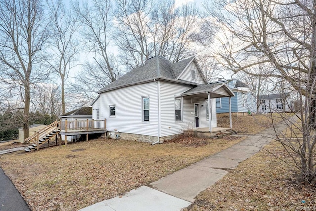 view of front of property with a shingled roof, a deck, and a front yard