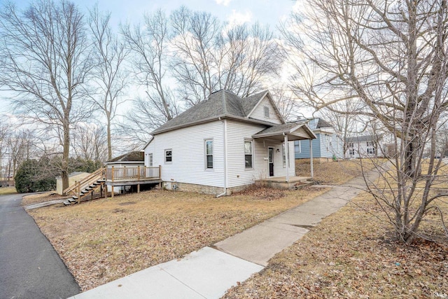 view of side of home with a deck, a yard, and roof with shingles