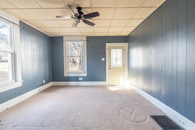 interior space with a ceiling fan, visible vents, a drop ceiling, and baseboards