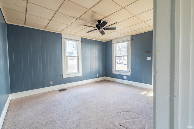 empty room featuring carpet floors, a paneled ceiling, visible vents, and a ceiling fan