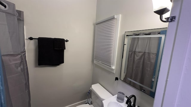 bathroom featuring curtained shower, a sink, and toilet