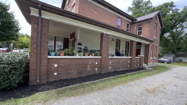 view of side of home with a porch and brick siding