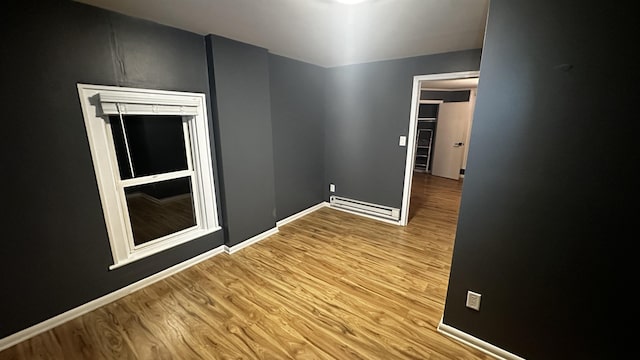 spare room with a baseboard radiator, baseboards, and wood finished floors