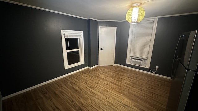 unfurnished dining area with cooling unit, crown molding, baseboards, and wood finished floors