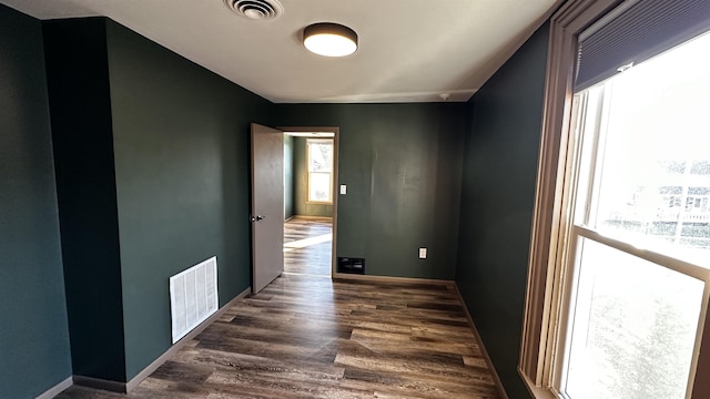 hallway featuring dark wood-style flooring, visible vents, and baseboards