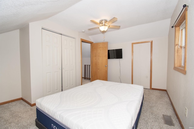 bedroom featuring a closet, light colored carpet, visible vents, vaulted ceiling, and baseboards