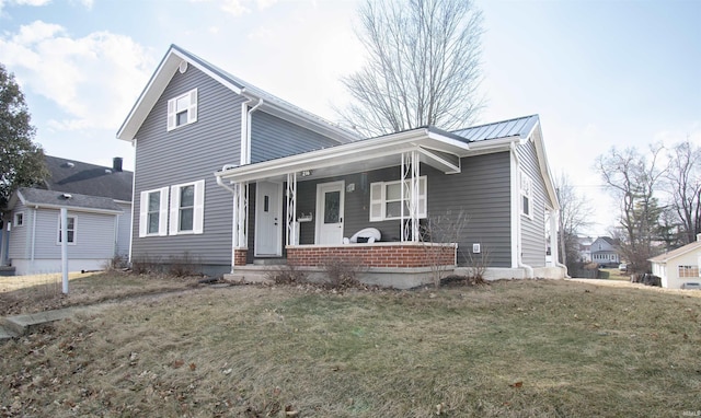 traditional-style house featuring covered porch, metal roof, and a front lawn