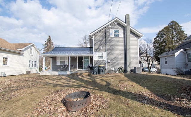 rear view of house featuring central air condition unit, covered porch, a chimney, and metal roof