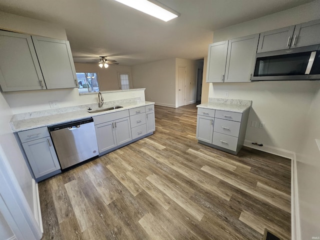 kitchen featuring stainless steel appliances, wood finished floors, a sink, and gray cabinetry