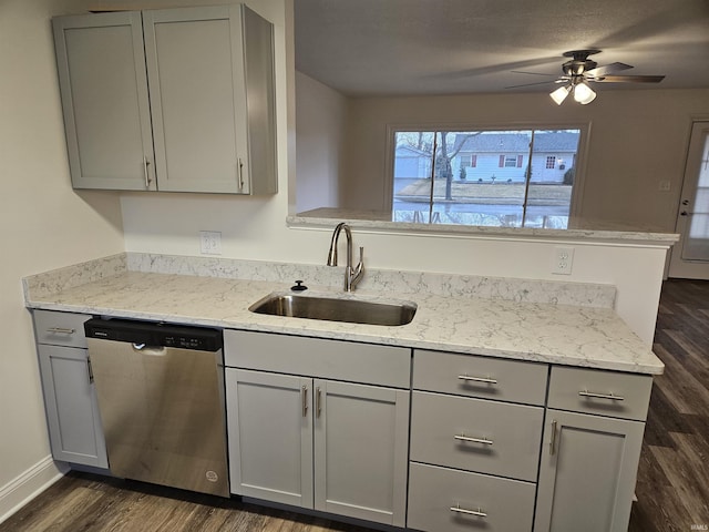 kitchen featuring stainless steel dishwasher, a sink, dark wood finished floors, and gray cabinetry