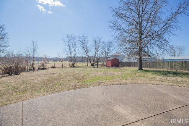 view of yard with a patio area, fence, an outdoor structure, and a storage shed