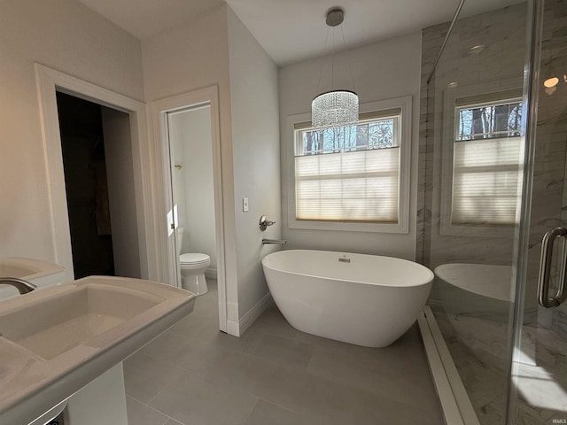 full bathroom featuring a freestanding tub, toilet, a sink, baseboards, and a shower stall