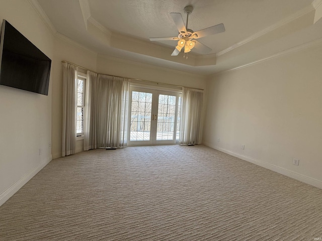 carpeted empty room featuring ornamental molding, french doors, a tray ceiling, and plenty of natural light