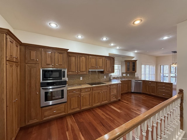 kitchen with brown cabinetry, appliances with stainless steel finishes, decorative backsplash, and dark wood-style flooring