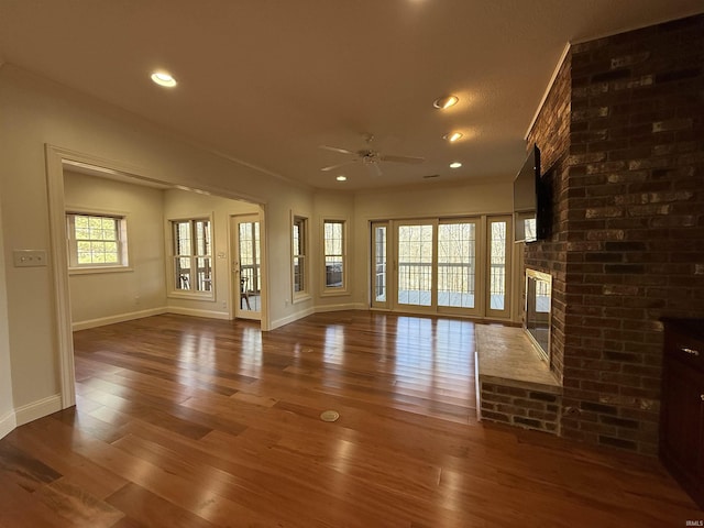 unfurnished living room featuring baseboards, a brick fireplace, hardwood / wood-style flooring, and recessed lighting