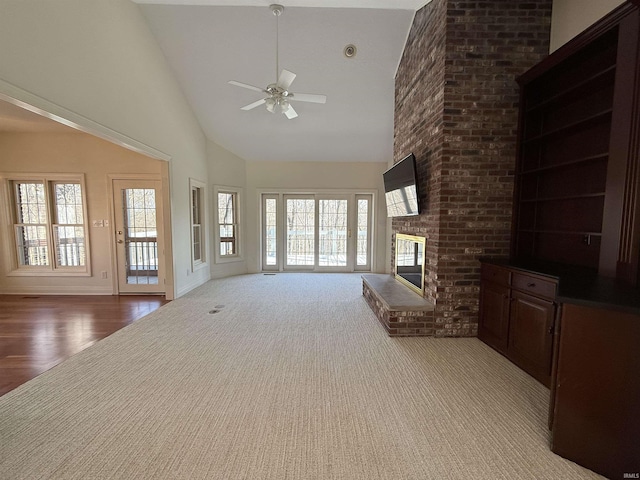 unfurnished living room with high vaulted ceiling, a fireplace, a wealth of natural light, and a ceiling fan