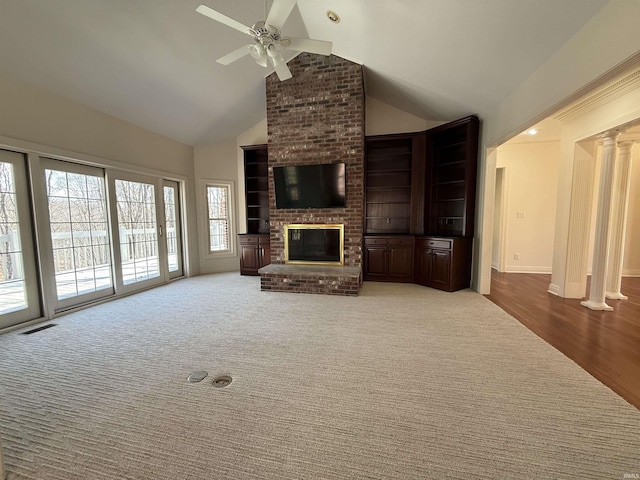 unfurnished living room featuring high vaulted ceiling, carpet floors, visible vents, a brick fireplace, and ornate columns