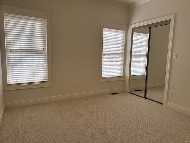 unfurnished bedroom with a closet, baseboards, carpet flooring, and multiple windows