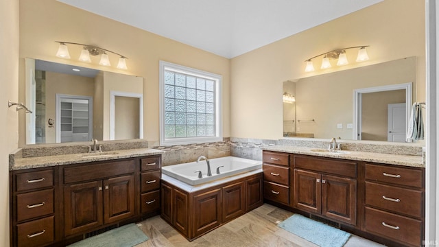 bathroom with a garden tub, two vanities, and a sink