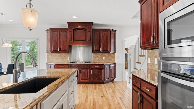 kitchen with appliances with stainless steel finishes, reddish brown cabinets, and a sink