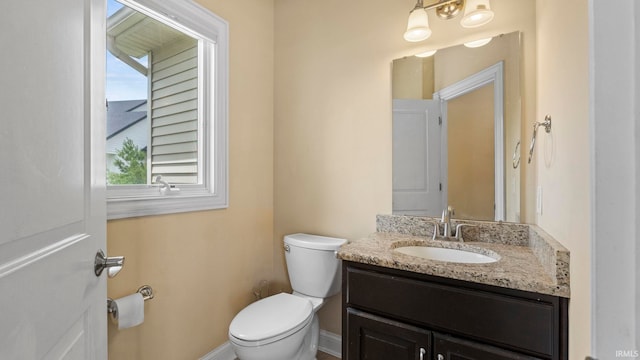 bathroom with toilet, baseboards, and vanity