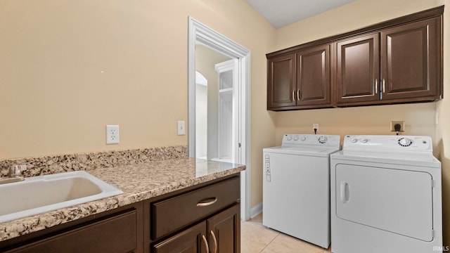 laundry area with cabinet space, light tile patterned floors, washer and dryer, and a sink