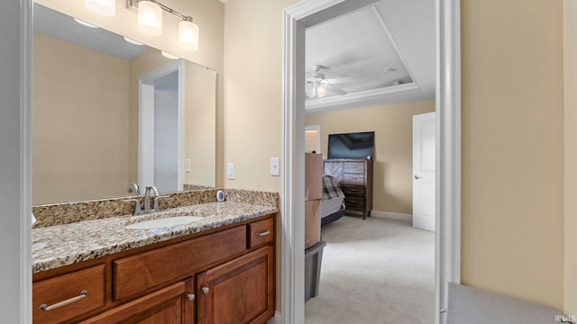 bathroom featuring baseboards, a tray ceiling, vanity, and a ceiling fan