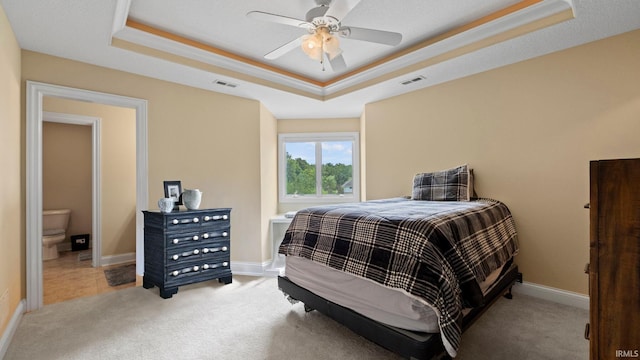 bedroom featuring a tray ceiling, visible vents, and light colored carpet