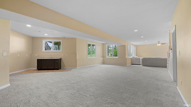 unfurnished living room featuring a wealth of natural light, light carpet, baseboards, and recessed lighting