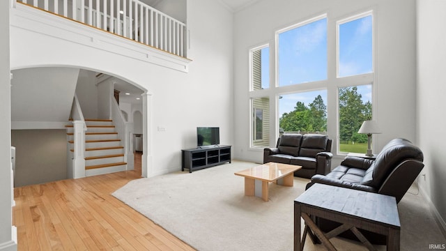 living room featuring stairs, a high ceiling, arched walkways, and hardwood / wood-style floors