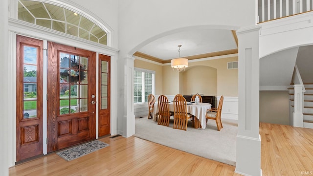 entrance foyer featuring arched walkways, crown molding, light wood finished floors, an inviting chandelier, and stairs