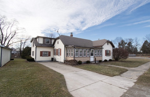 view of front of house with concrete driveway, a chimney, roof with shingles, cooling unit, and a front yard