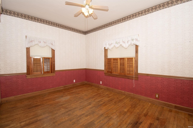 spare room featuring wallpapered walls, baseboards, a wainscoted wall, ceiling fan, and hardwood / wood-style floors