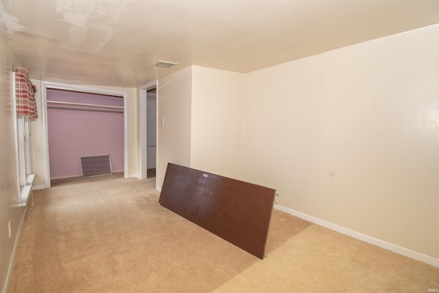 spare room with baseboards, visible vents, and light colored carpet